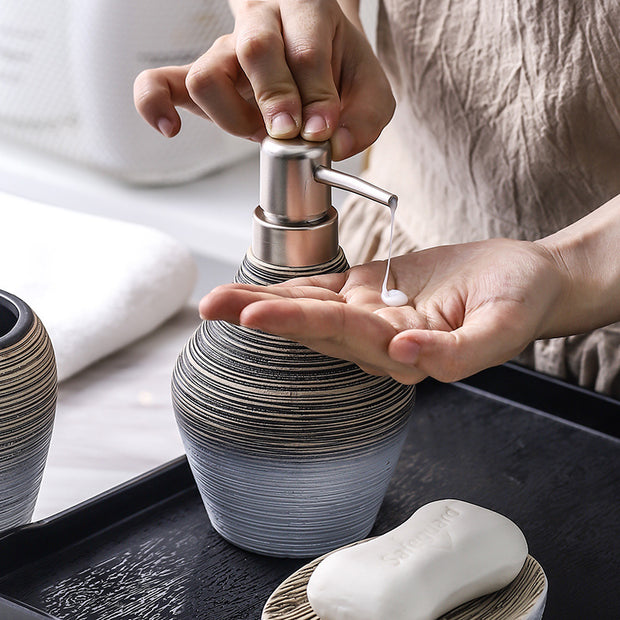 Person dispensing soap from a retro brushed ceramic bathroom wash set.