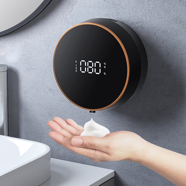 Automatic induction hand sanitizer machine dispensing foam into a hand, featuring a digital display on the wall.